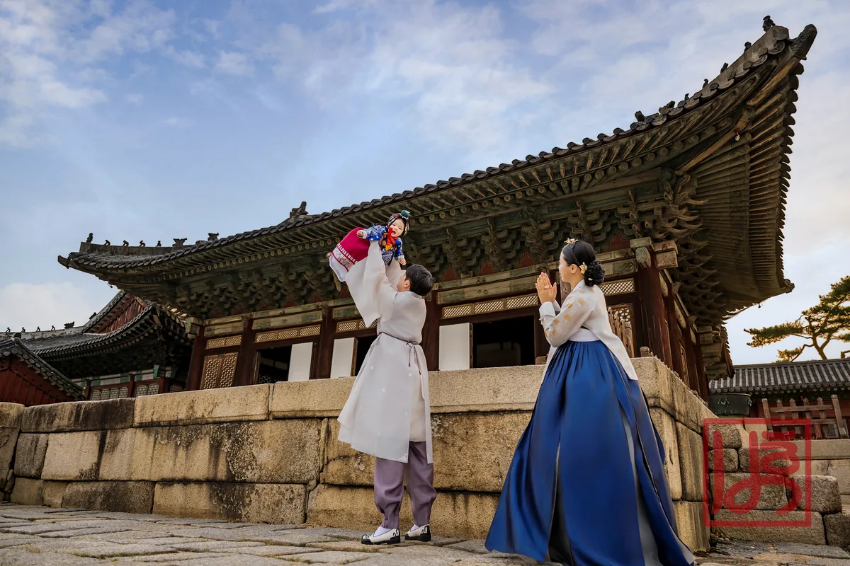 고궁을 배경으로 부모와 함께한 자주색 돌한복 아기와 남색 치마 한복