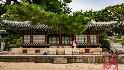 고궁 마당에서 남색 치마와 회색 저고리를 입고 아이를 안아 올리는 모습