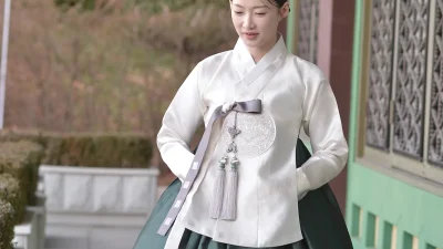 아이보리 저고리와 짙은 녹색 치마에 노리개를 더한 우아한 여성 한복