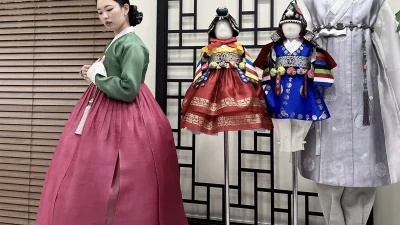 초록 저고리와 수복문 자주 치마의 여성 한복이 매장에 전시된 돌한복들과 어우러진 모습