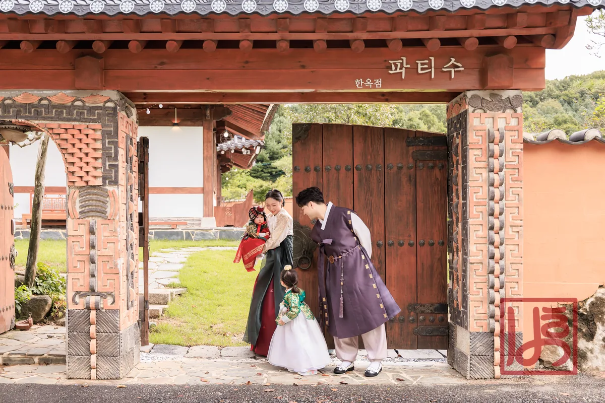 가슴 중앙에 자리한 모란 자수 흉배와 소매 끝 나비 자수가 돋보이는 돌한복, 은은한 배경