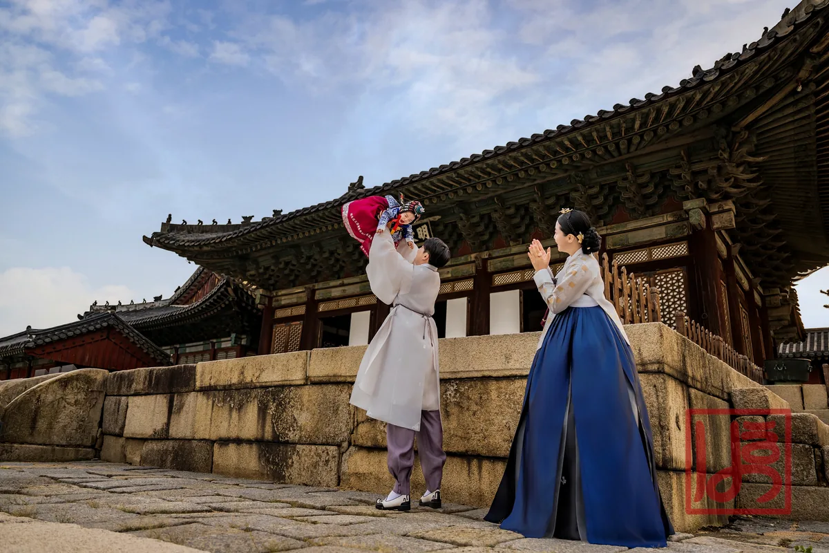 고궁을 배경으로 부모와 함께한 자주색 돌한복 아기와 남색 치마 한복