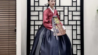 금빛 흉배 장식이 돋보이는 자주색 저고리와 짙은 남색 치마의 혼주 한복