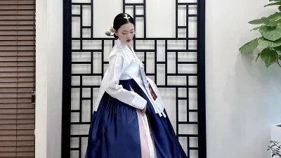 흰 저고리와 화려하게 펼쳐진 남색 치마가 우아한 여성 한복